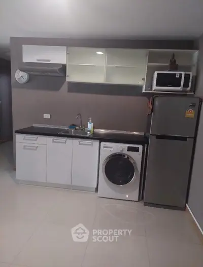 Modern compact kitchen with washing machine and fridge, ideal for urban living.