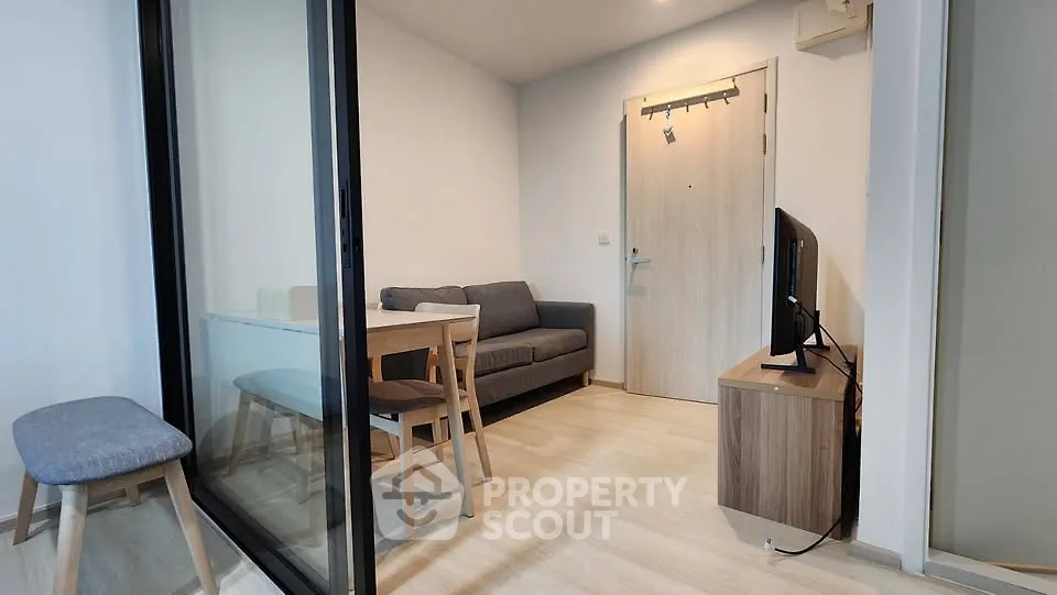 Modern living room with glass partition, cozy sofa, and sleek wooden furniture.