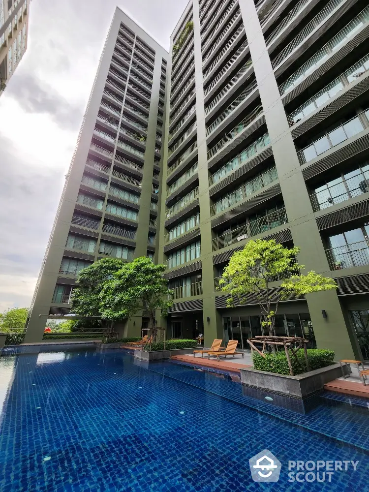 Luxurious high-rise building with stunning poolside view and lush greenery