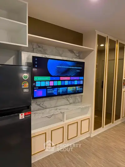 Modern living room with stylish TV setup and sleek refrigerator in contemporary apartment.