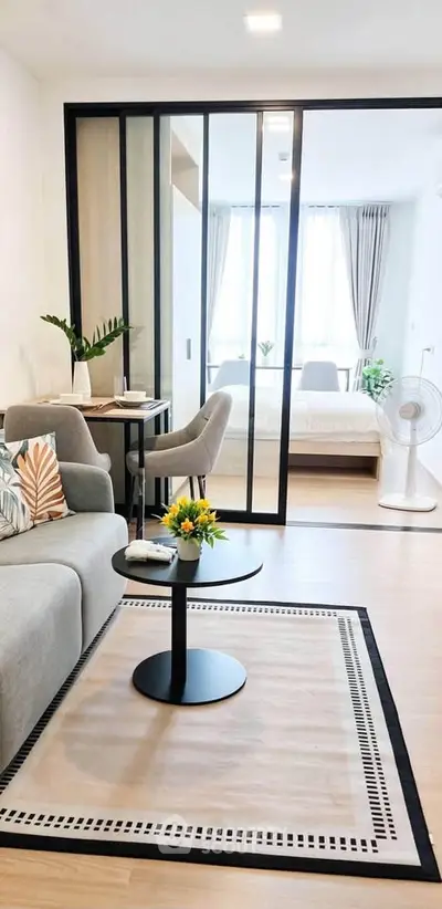 Modern living room with sliding glass doors leading to a bright bedroom, featuring stylish decor and cozy ambiance.