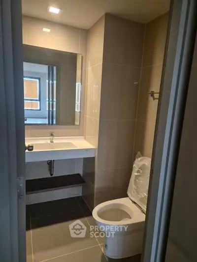Modern bathroom with sleek fixtures and large mirror in contemporary apartment.