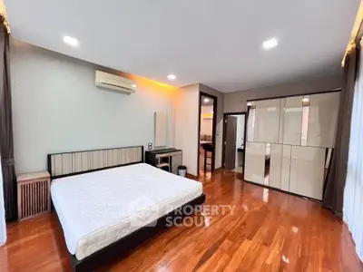 Spacious bedroom with wooden flooring and modern furniture