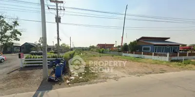 Vacant land plot with potential for development in a suburban area, featuring clear skies and surrounding greenery.