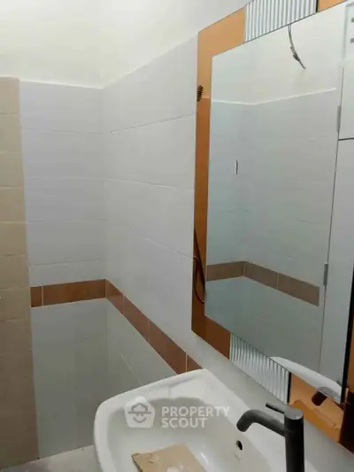 Modern bathroom with sleek sink and mirror, featuring stylish tile accents.
