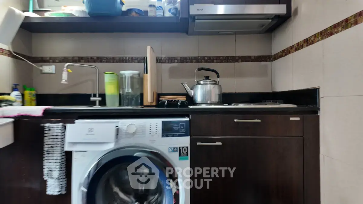 Compact kitchen with washing machine and modern appliances in cozy apartment.