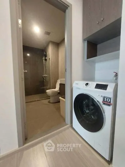 Modern bathroom with washing machine and shower in sleek apartment.