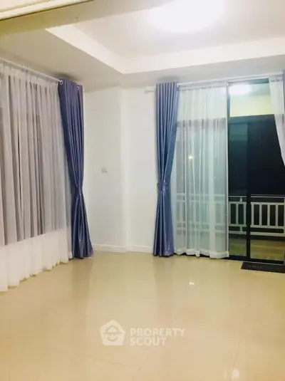 Spacious empty living room with elegant curtains and large windows.