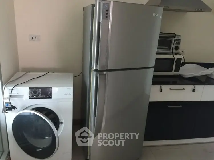 Modern kitchen with stainless steel fridge and washing machine