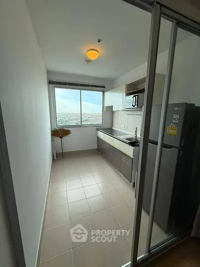 Modern kitchen with sleek cabinetry and large window offering stunning city views.