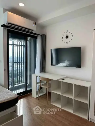 Modern bedroom with balcony view, wall-mounted TV, and sleek desk setup.