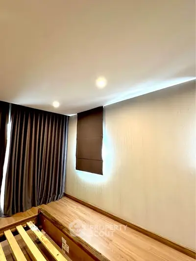 Spacious bedroom with wooden flooring and large windows for natural light.