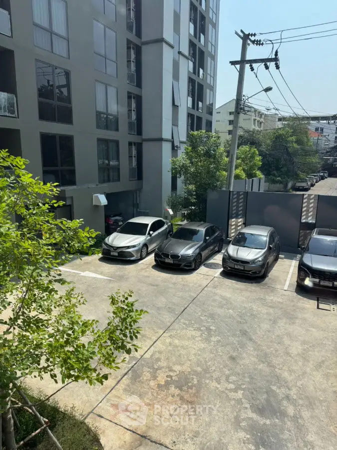 Modern apartment building with parking area and luxury cars in urban setting.