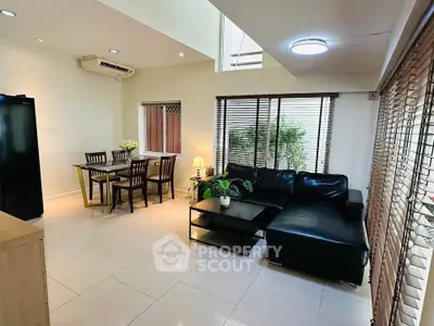 Spacious living room with modern furniture and dining area, featuring large windows and natural light.