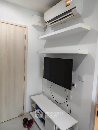 Modern living room corner with wall-mounted TV and air conditioning unit.