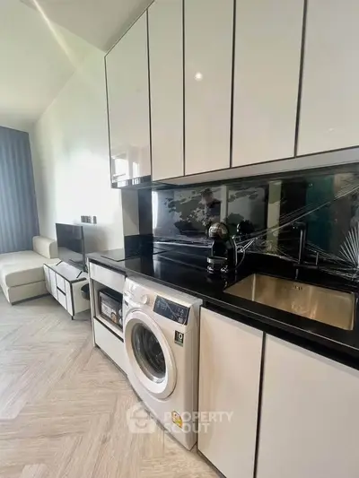 Modern kitchen with sleek cabinetry and built-in washing machine in stylish apartment.