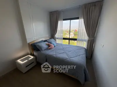 Cozy bedroom with large window offering a stunning city view, featuring modern decor and ample natural light.
