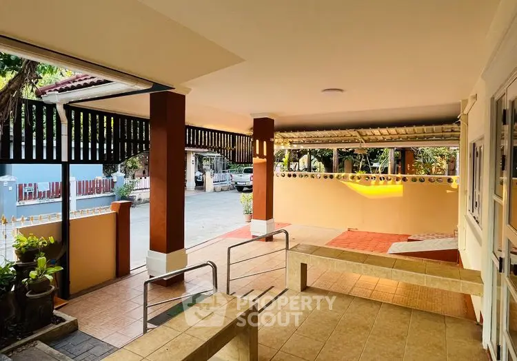 Charming covered patio with tiled flooring and garden view, perfect for relaxation and outdoor gatherings.
