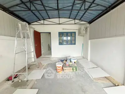 Spacious interior renovation with ladder and paint supplies, featuring a red door and blue window.