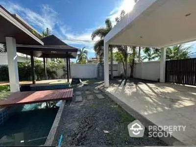 Spacious outdoor area with pool and covered patio in tropical setting