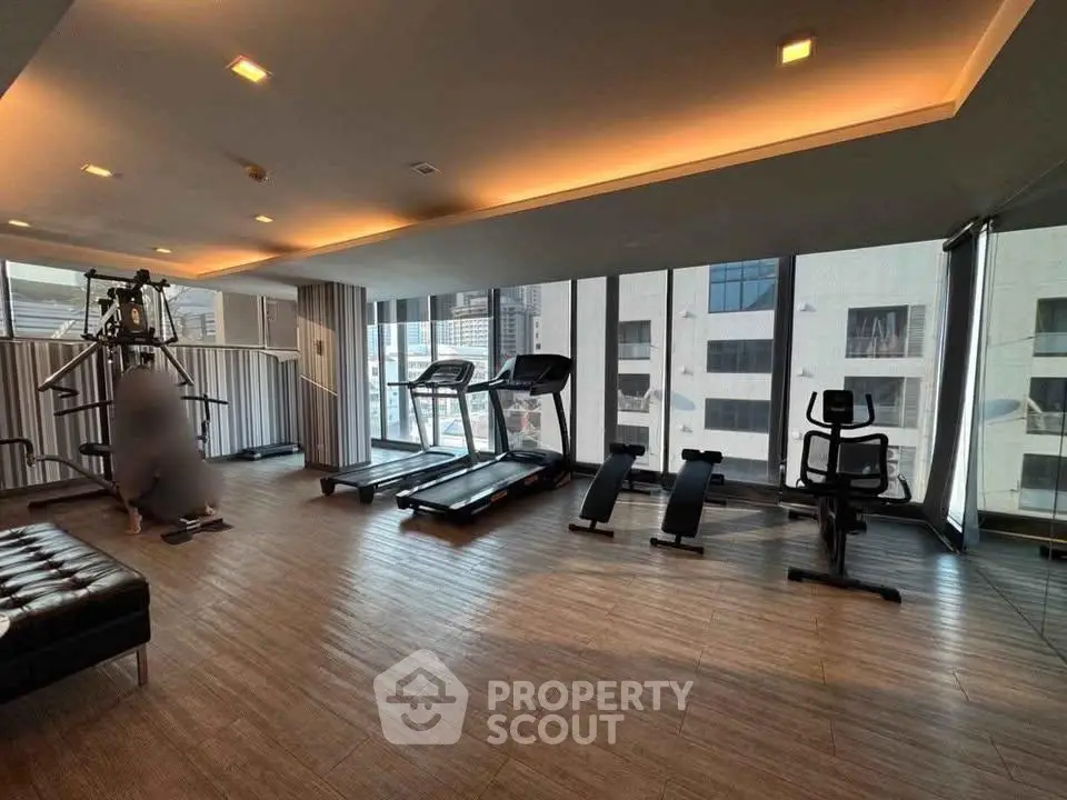 Modern gym with city view, featuring treadmills and exercise equipment in a sleek, well-lit space.
