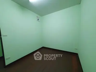 Spacious empty room with mint green walls and dark wood flooring, perfect for customization.