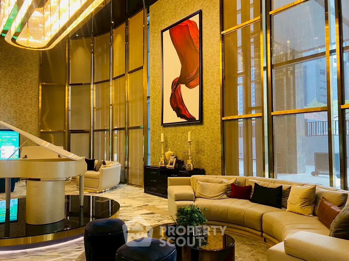 Luxurious modern lobby with elegant seating and grand chandelier in upscale building.