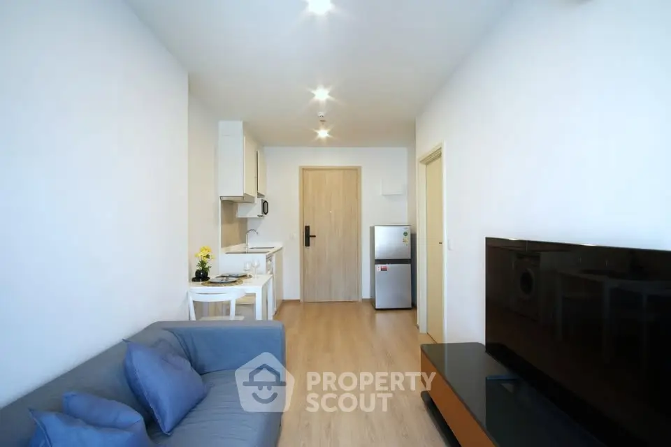 Modern living room with sleek furniture and compact kitchen in a cozy apartment.