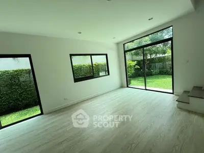 Spacious living room with large windows overlooking lush garden