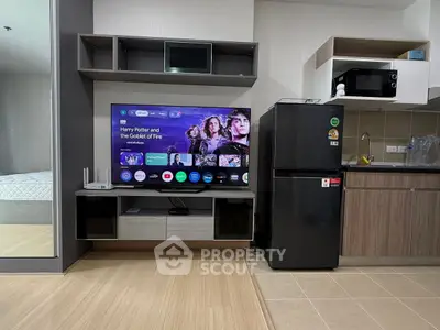 Modern living room with sleek kitchen, featuring a smart TV and contemporary appliances.