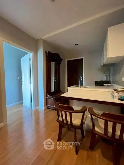 Charming kitchen with open layout and wooden flooring, featuring elegant dining chairs and modern cabinetry.