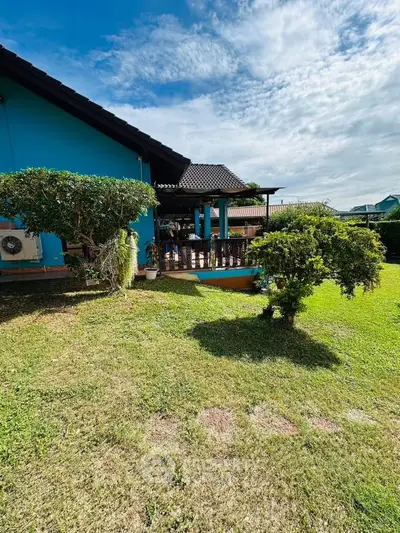 Charming blue house with lush garden and spacious patio under a clear sky.