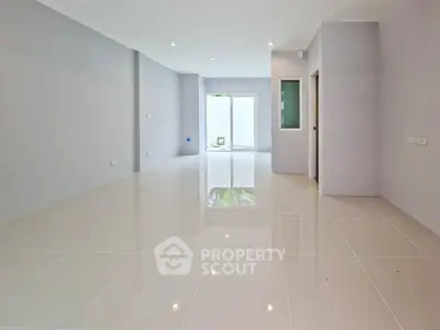 Spacious empty living room with glossy tiled floors and large windows