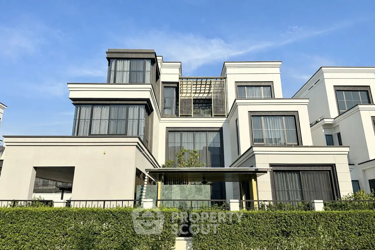 Modern multi-story building with large windows and lush greenery, showcasing contemporary architecture.