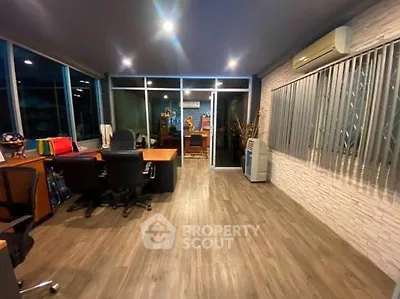 Spacious modern office with sleek wooden flooring and large windows for natural light.