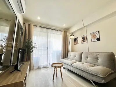 Modern living room with stylish decor, cozy sofa, and natural light from large window.