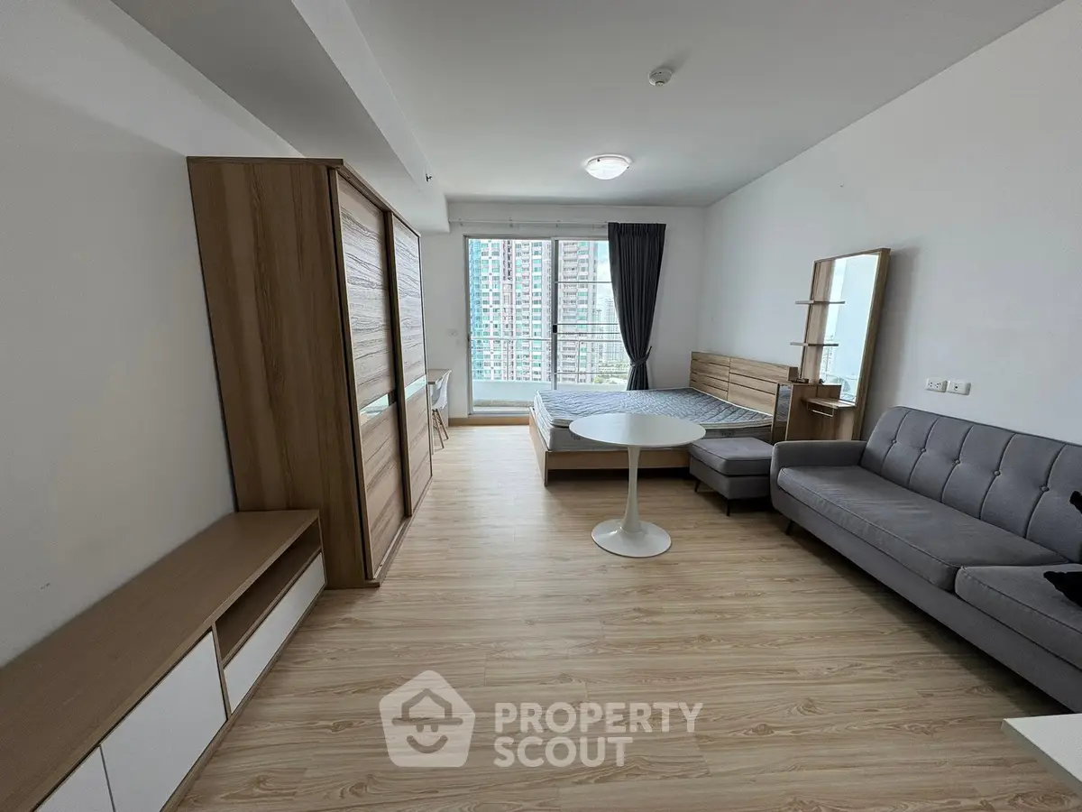 Modern studio apartment with stylish furnishings and large windows offering city views.