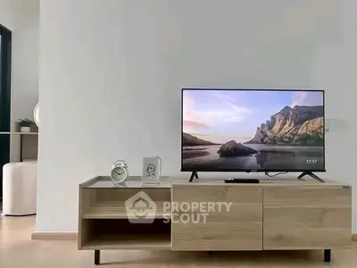 Modern living room with sleek TV stand and flat-screen TV displaying scenic view.