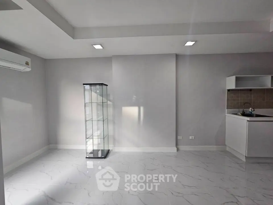 Modern minimalist interior with sleek white flooring and compact kitchen area