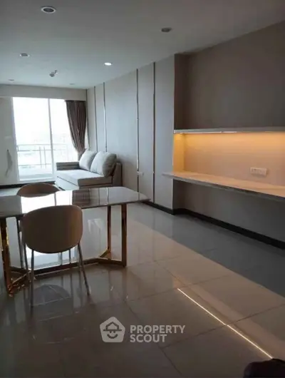 Modern living room with sleek design and large windows offering natural light and balcony access.
