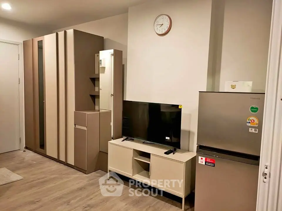 Modern living room with sleek furniture and appliances, featuring a TV and refrigerator for a cozy lifestyle.