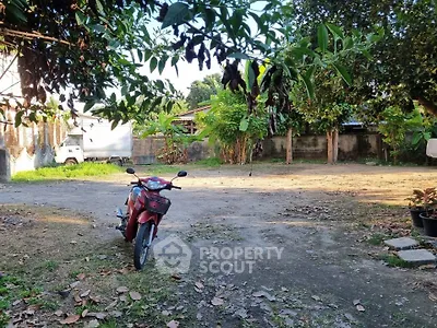 Spacious outdoor area with lush greenery and ample parking space, ideal for residential or commercial use.