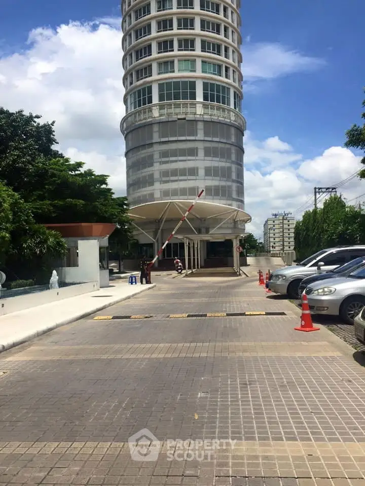 Modern high-rise building entrance with parking area and clear blue sky