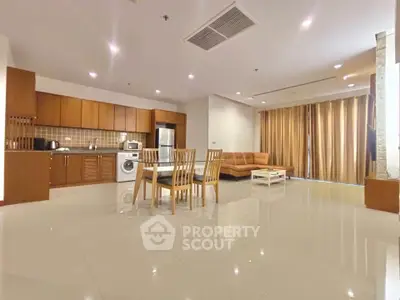 Spacious open-plan living room with modern kitchen and dining area, featuring sleek appliances and elegant furnishings.