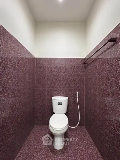 Modern bathroom with maroon tiles and sleek toilet design