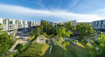 Modern residential complex with lush green landscaping and contemporary architecture under a clear blue sky.