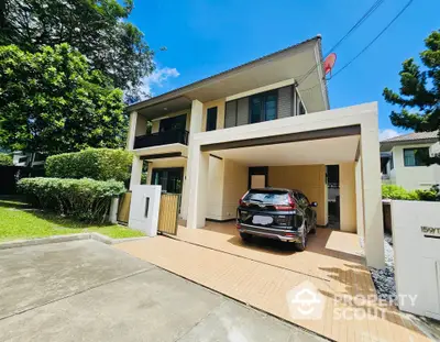 Modern two-story house with carport and lush garden in a serene neighborhood.