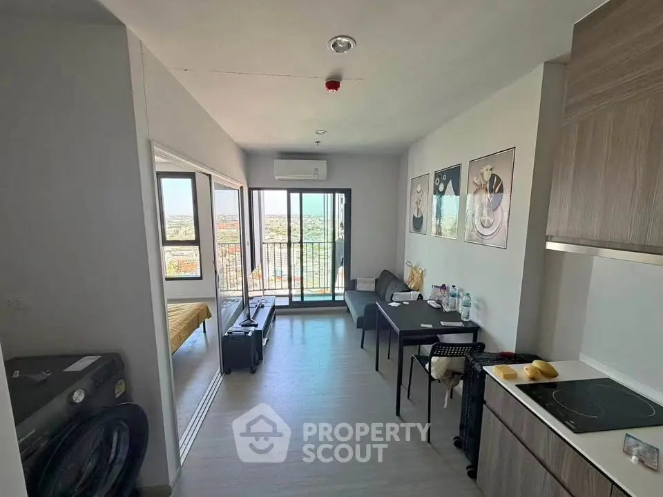 Modern living room with balcony and city view, featuring sleek furniture and contemporary decor.