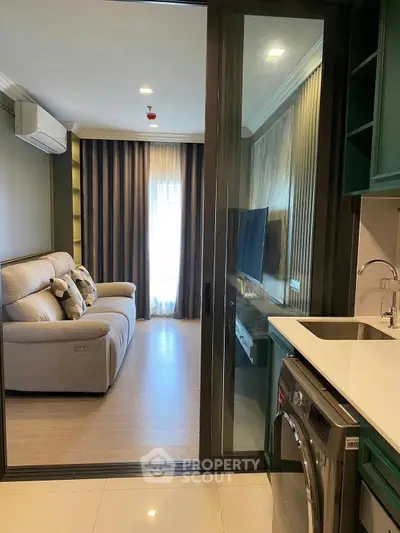 Modern apartment with sleek kitchen and cozy living room, featuring a washing machine and stylish decor.