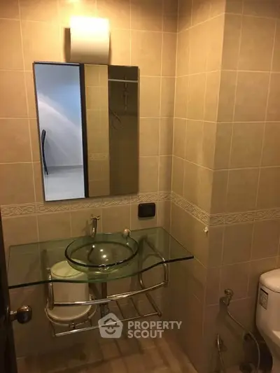 Modern bathroom with glass sink and tiled walls in a stylish apartment.